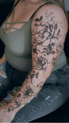 a woman sitting on top of a couch with flowers tattooed on her arm and leg