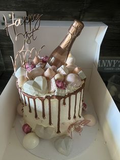 a birthday cake in a box with a bottle of champagne