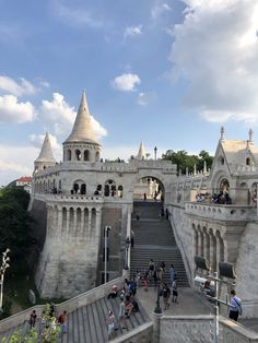 people are walking up and down the stairs in front of an old castle like building