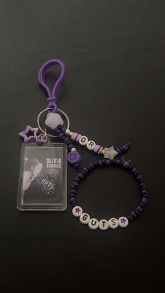 a purple lanyard with beads and charms attached to it, sitting on a black surface