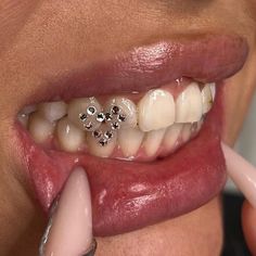 a close up of a woman's teeth with diamond studs on her tongue