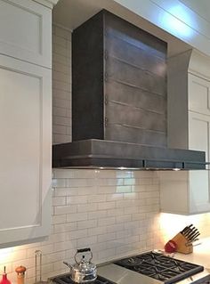 a stove top oven sitting inside of a kitchen next to white cabinets and counter tops