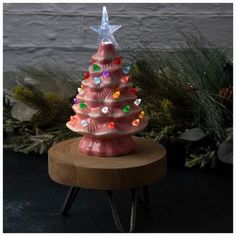 a pink ceramic christmas tree sitting on top of a wooden table next to a wall