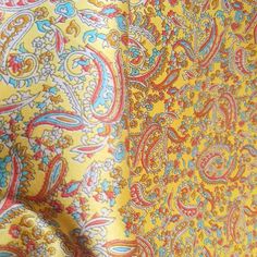 a yellow and blue paisley print fabric with red, white, and blue designs on it