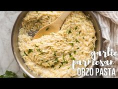 a pan filled with pasta and parsley on top of a table next to a wooden spoon