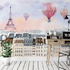 a wall mural with hot air balloons in the sky above buildings and a clock on a table