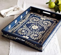 a blue and gold tray sitting on top of a table next to two lemons