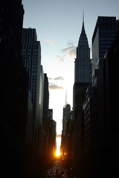 the sun is setting behind tall buildings in new york city's financial district, as seen from an alleyway