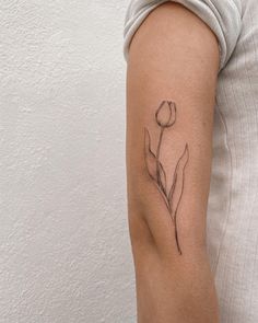 a woman's arm with a single flower tattoo on the left side of her arm