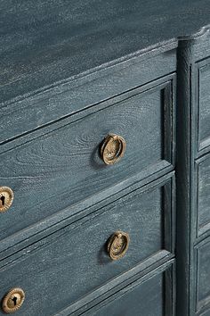 a blue dresser with brass pulls and knobs on it's drawers, showing the handles