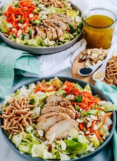 two bowls filled with salad and chicken on top of a table