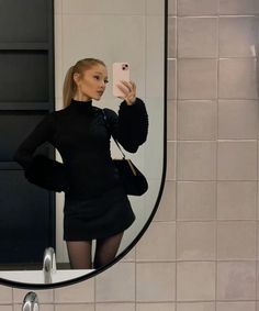 a woman taking a selfie in front of a mirror with her cell phone and handbag