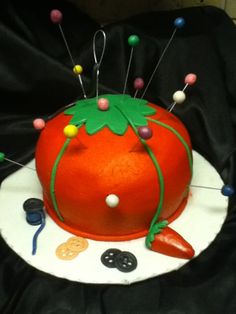 an orange cake with pins and needles on it