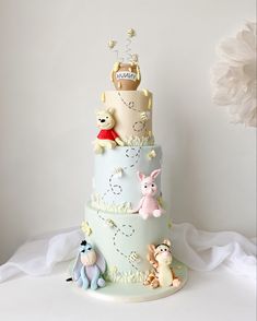 a three tiered cake with winnie the pooh characters on it, and other decorations