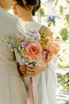 a bride and groom holding flowers in their hands