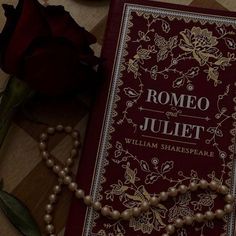 a red book with pearls on it next to a rose and other items that are laying on the floor