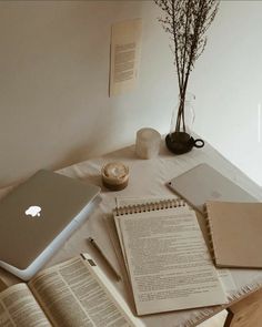 an open laptop computer sitting on top of a table next to books and notebooks