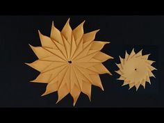 two pieces of paper that look like sunflowers on a black background, one is yellow and the other is white