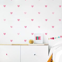 a white dresser with pink hearts on it and a wall sticker in the background