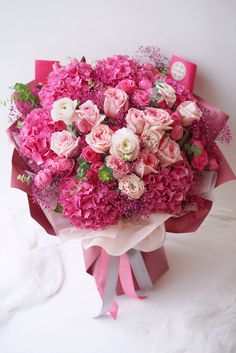 a bouquet of pink and white flowers is wrapped in red ribbon on a white background