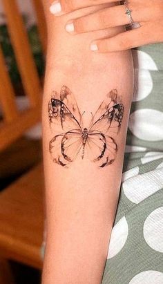 a woman's arm with a butterfly tattoo on the left side of her arm