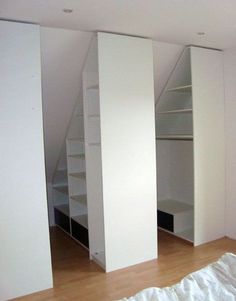 an empty room with white closets and shelving in the corner next to a bed