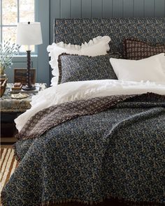 a bed with blue and white bedspread in a bedroom next to a window