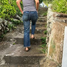 a woman is walking up some steps in the woods with her back to the camera