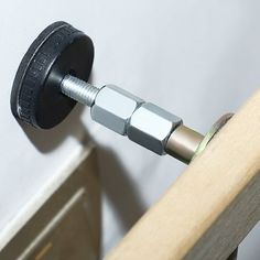 a close up of a metal object on a wooden rail with a white wall in the background