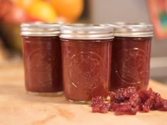 three jars filled with jam sitting on top of a wooden table