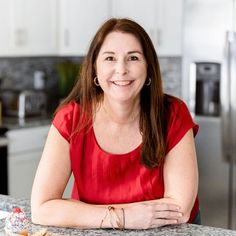 a woman sitting at a kitchen counter smiling