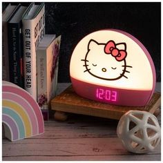 a hello kitty alarm clock sitting on top of a wooden table next to some books