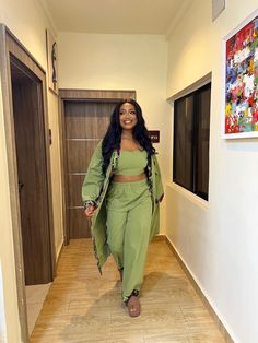 a woman is standing in the hallway wearing green pants and a top with an attached belt