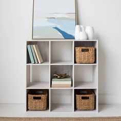 a white shelf with baskets and books on it