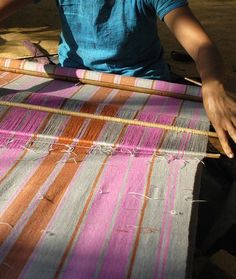 a woman is weaving fabric on an old loom