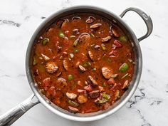 a pot filled with meat and vegetables on top of a marble countertop next to a spoon