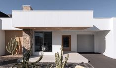 a white house with cactus in front of it and two doors on the side of the house