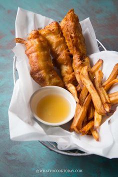 fried fish and fries with dipping sauce in a basket on a blue tableclothed surface