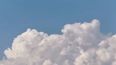 an airplane is flying high in the sky above some white fluffy clouds and blue skies