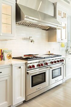 a stove top oven sitting inside of a kitchen next to white cabinets and counter tops