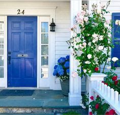 a blue front door with white trim and flowers