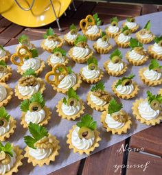 small cupcakes with white frosting and green garnish are arranged on a table