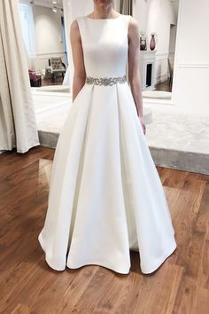 a woman in a white dress standing on a wooden floor