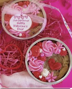 two tins filled with valentine's cookies on top of a pink table cloth