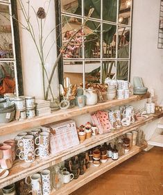 the shelves are full of mugs and other items in front of a large mirror