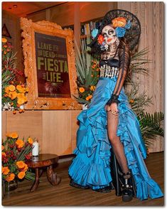 a woman in a blue dress with flowers on her head is posing for the camera