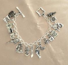 I love the feel of a charm bracelet as the charms dangle playfully around the wrist.  This is a pirate themed charm bracelet, and it is chocked full of pirate themed charms.  There are a total of 17 charms, each one different.  The charms include skulls, ship, sword, flag, pirates, and so many more.  The charms are silver tone and hang from a soldered silver tone chain and it ends with a squared silver tone toggle clasp.  The bracelet measures approximately 8 inches. Pirate Jewelry Women, Female Pirate Jewelry, Pirate Jewelry Bracelets, Pirates Of The Caribbean Pendant, Adjustable Ocean-inspired Charm Bracelet With Lobster Clasp, Charm Bracelet Silver, Hook Bracelet, Captain Hook, Pirate Theme