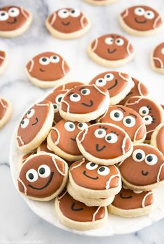 a plate full of ginger cookies with eyes and noses on them, ready to be eaten