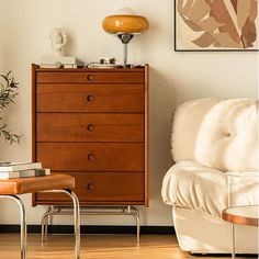 a living room with a white couch and wooden dresser next to a painting on the wall