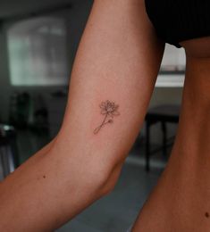 a woman's arm with a small flower tattoo on the left side of her body